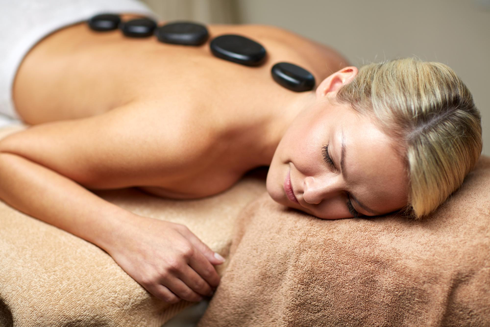 Entspannte Frau bei einer Hot Stone Massage in Frankfurt – schwarze Basaltsteine auf dem Rücken für tiefe Wärmebehandlung