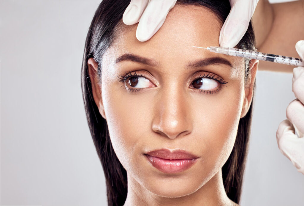Ärztin injiziert Botox oder Hyaluron zur Faltenbehandlung in die Stirn einer Frau